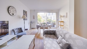A modern living room with a sofa, a dining table, and a TV. - Lovely  apartment with exceptional terrace (Bordeaux)