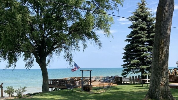 Un parque con una terraza de madera, sillas e una bandera.