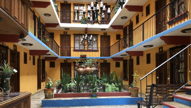 Un vaste atrium doté d’une fontaine centrale, entouré de plantes en pot et d’un escalier menant aux étages supérieurs.