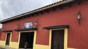 Un bâtiment à la façade rouge et jaune, avec deux portes et un pot de fleurs placé à l’extérieur.