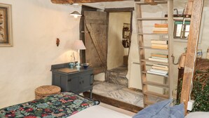 Un dormitorio rústico con cama, una escalera de madera, un aparador y una estantería.