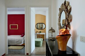 A bedroom with a red wall, a bed, a mirror, and a dresser with a vase. - Apt. near S.Peter & beautiful terrace (Roma)