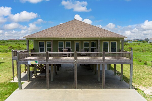 A two-story building with a balcony, wooden deck, and a sign indicating it is a 'Resort'. - Ocean view, backyard playset and fire pit, game room, great for kids and pets! (Crystal Beach)
