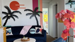 Uma sala de estar moderna com um sofá azul, uma mesa de centro redonda e um mural de parede vibrante.
