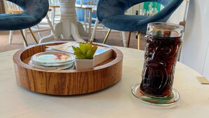 Mesa redonda com um suporte, um copo de chá gelado e uma pequena planta em vaso.