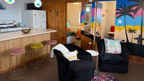 A room with a kitchen area, a bar, and a seating area with a mural.