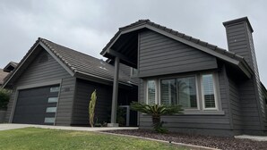 Una casa moderna de dos pisos con fachada gris oscuro, un porche cubierto y una chimenea.