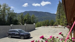 A parking area with a vehicle, a stone wall, and a mountain backdrop. - Kitimat Lodge (Kitimat)
