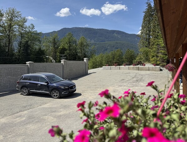 A parking area with a vehicle, a stone wall, and a mountain backdrop.