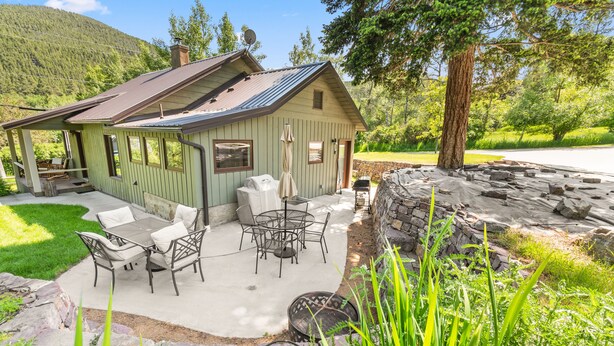Un chalet rustique doté d’un patio aménagé avec du mobilier d’extérieur et un barbecue.