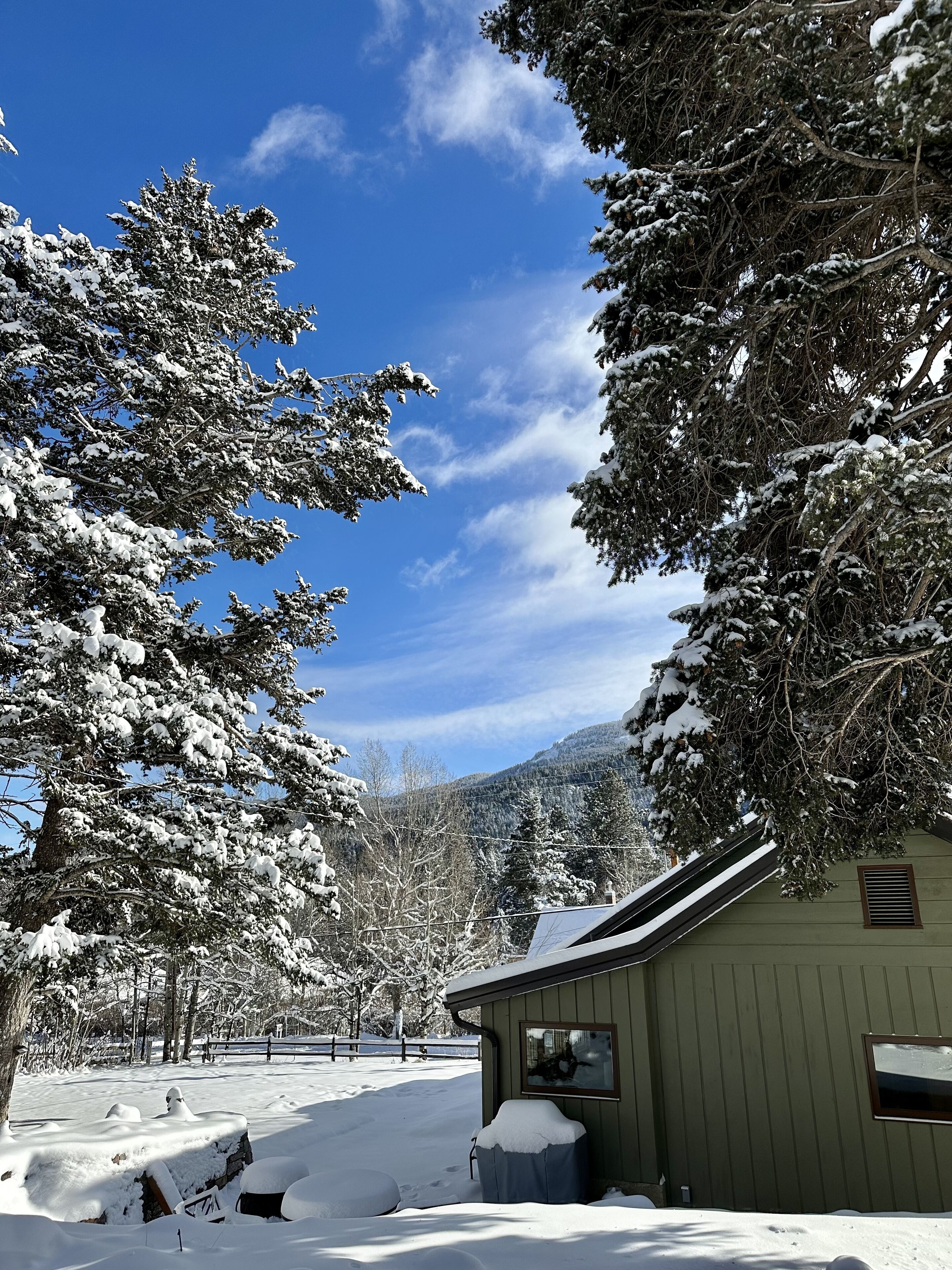 A cabin with a snow-covered landscape, a clear sky, and a mountain in the background.