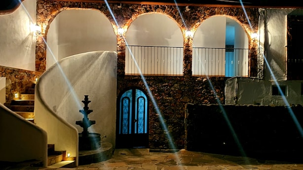 A stone-walled interior with a staircase, a blue door, and a fountain. - Hotel Beraka (Ezequiel Montes)