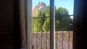 A room with a large window overlooking a mountain and a stone wall with a metal railing. - Hotel Beraka (Ezequiel Montes)