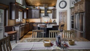 Una cocina rústica con armarios de madera, una mesa de comedor con sillas y un reloj en la pared.