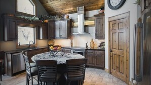 Una cocina con una mesa redonda, armarios de madera y un reloj en la pared.