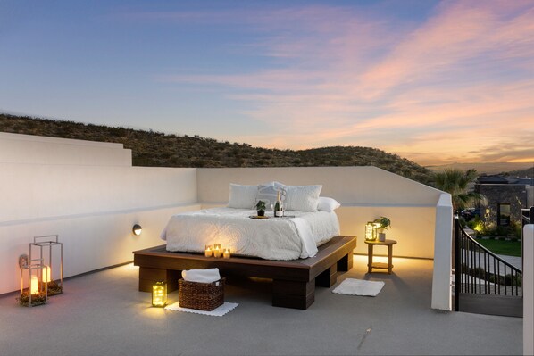 Relax on a spacious rooftop terrace with a large bed and scenic views of the surrounding hills.