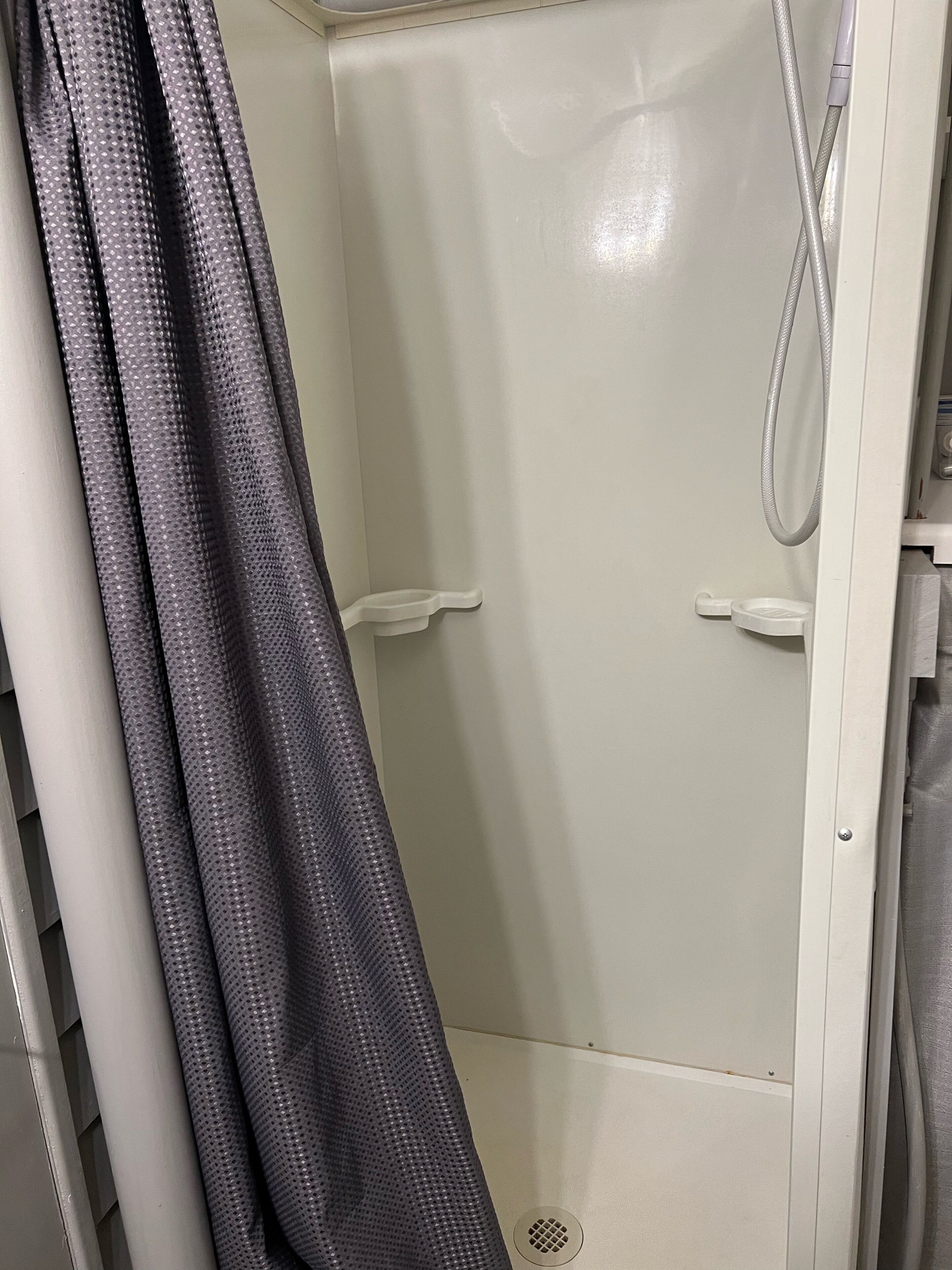 A shower area with a white door and a shower hose.