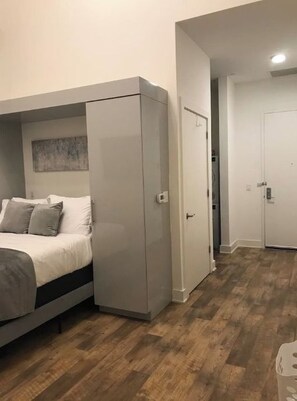 Une chambre à coucher comprenant un lit, une armoire et une porte donnant sur une autre pièce.