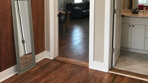A hallway with wooden flooring, a dining area with a table and chairs, and a kitchen with white cabinets and a sink. - 1.3 Mile Walk to the Augusta National Clubhouse!<br>Lovely Cottage with Space! (Augusta)