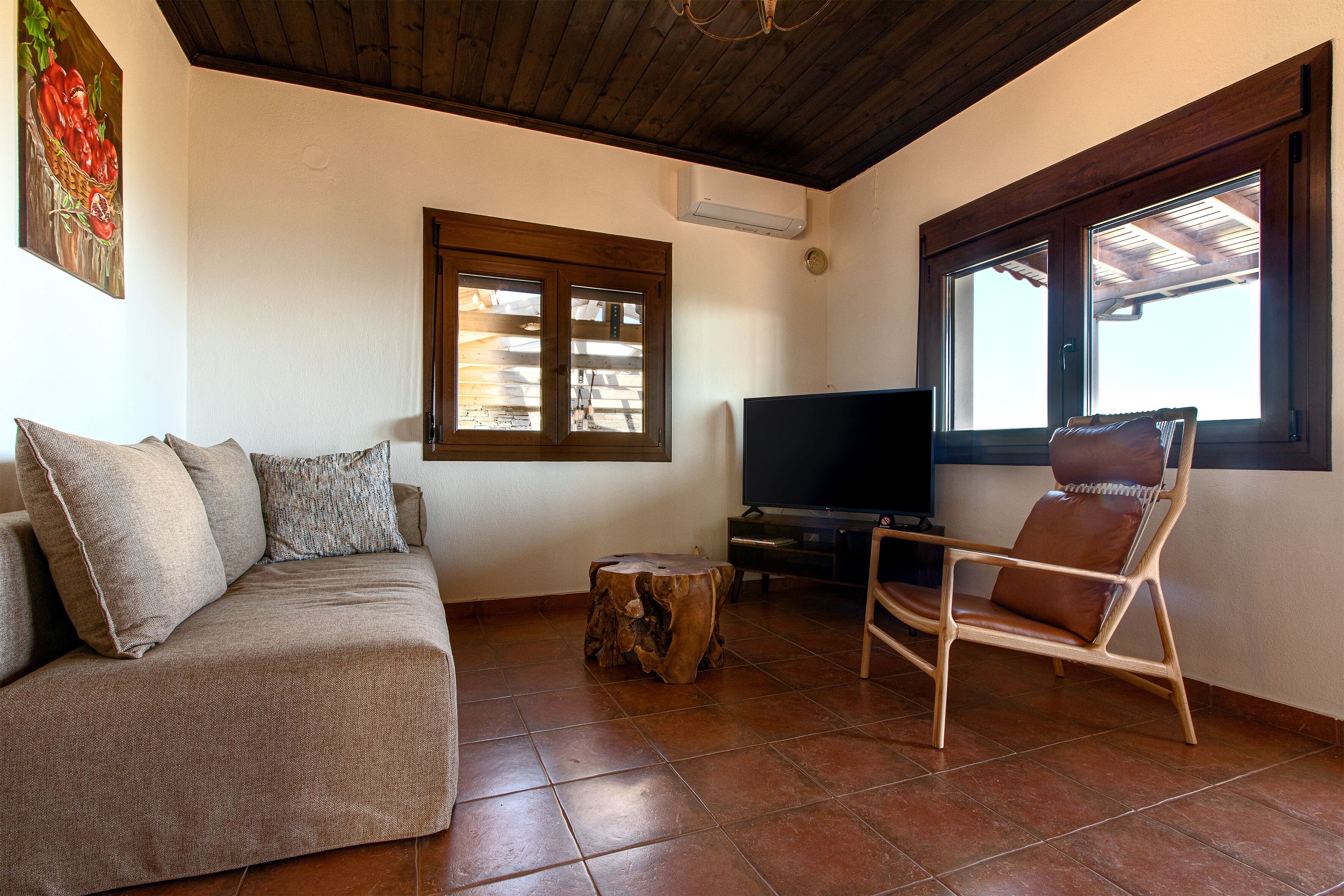 A living room with a sofa, a wooden coffee table, a TV, and a window with wooden shutters.