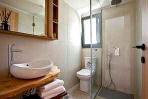A bathroom with a wooden vanity, white sink, and a glass shower enclosure.