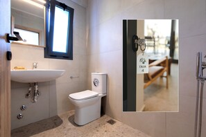 A modern bathroom with a white sink, toilet, and shower. - Casa Del Olivar (Aristotelis)