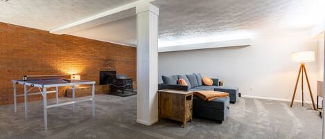 Una habitación con mesa de ping pong, sofá y lámpara.
