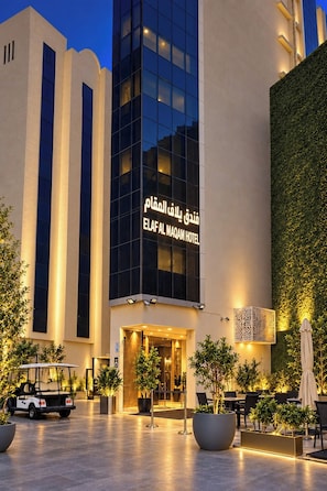 The exterior of the ELAF AL MAQAM HOTEL with a modern facade, illuminated entrance, and outdoor seating area. - Nour Al Thuria Hotel (Makkah)