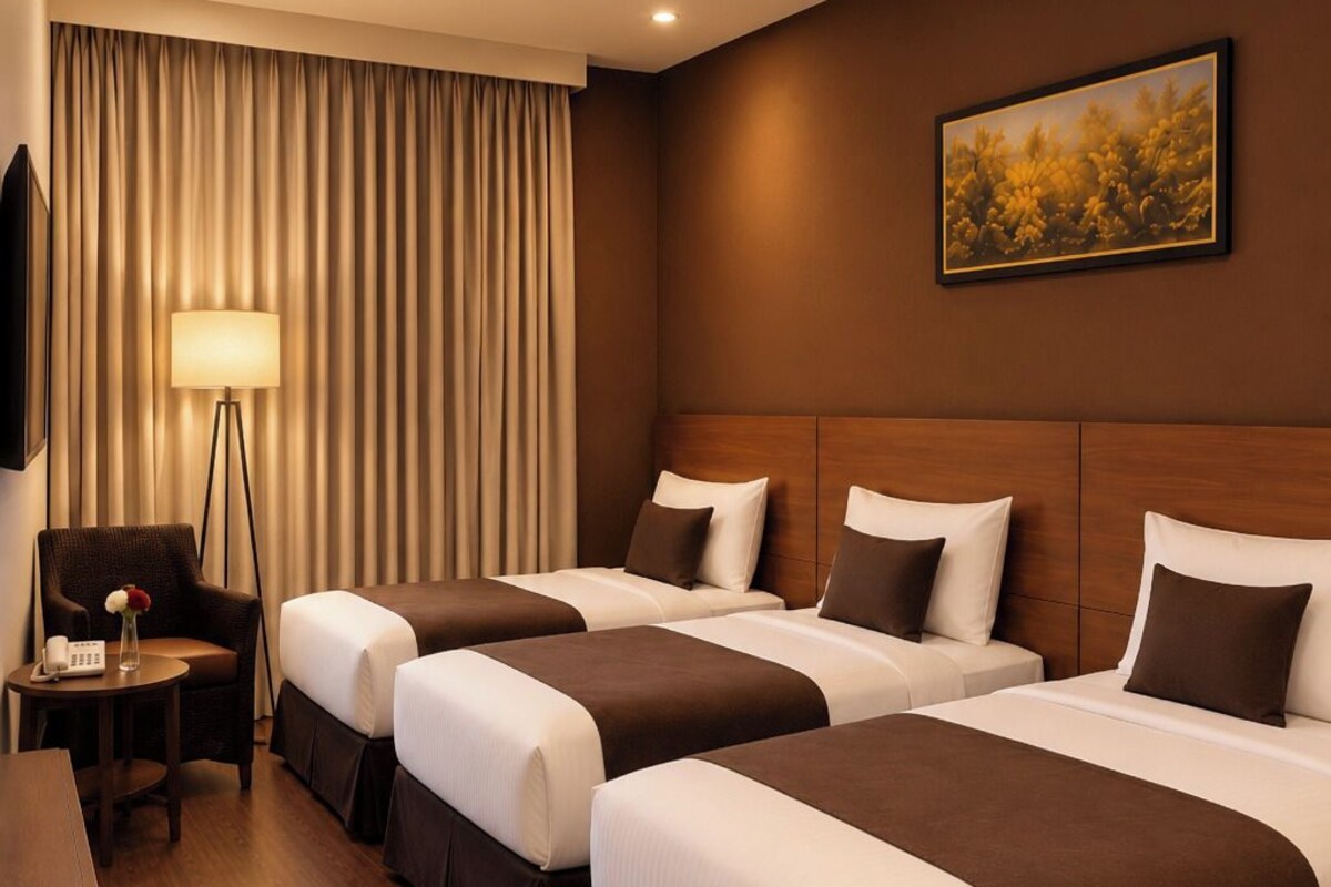 A hotel room with two beds, a desk, a lamp, and a painting on the wall.