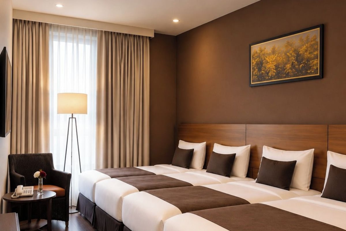 A hotel room with a large bed, a desk, a chair, a lamp, and a painting on the wall.