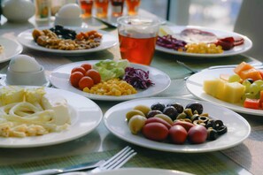 A table with various dishes including pasta, vegetables, and fruits, along with a glass of tea. - Nour Al Thuria Hotel (Makkah)