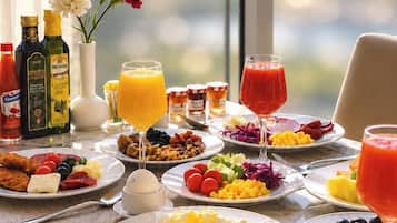 A breakfast table with various dishes, drinks, and condiments.