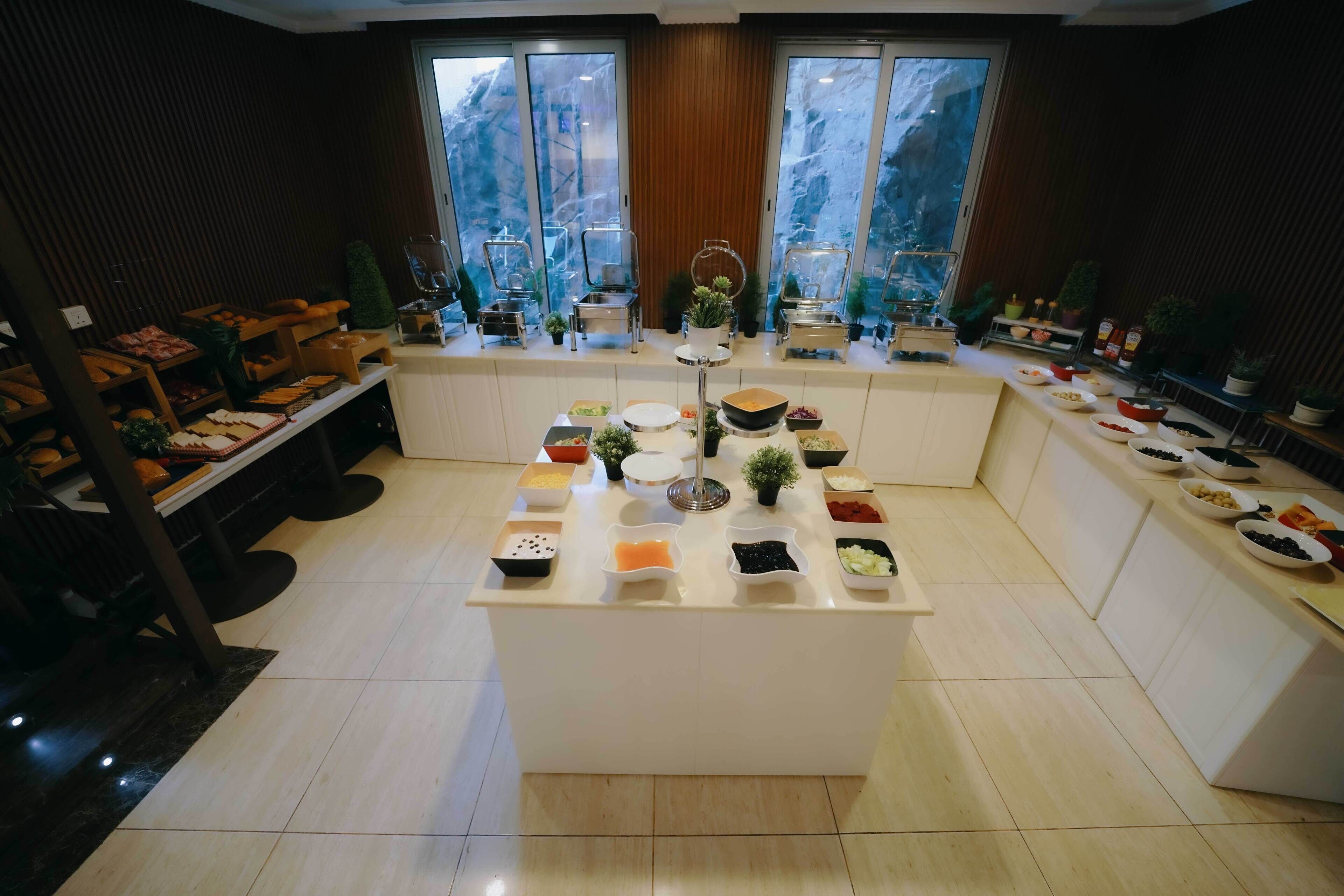Une cuisine moderne dotée d’un îlot central, de différents espaces dédiés à la préparation des aliments et offrant une vue sur un paysage montagneux grâce à de grandes fenêtres.