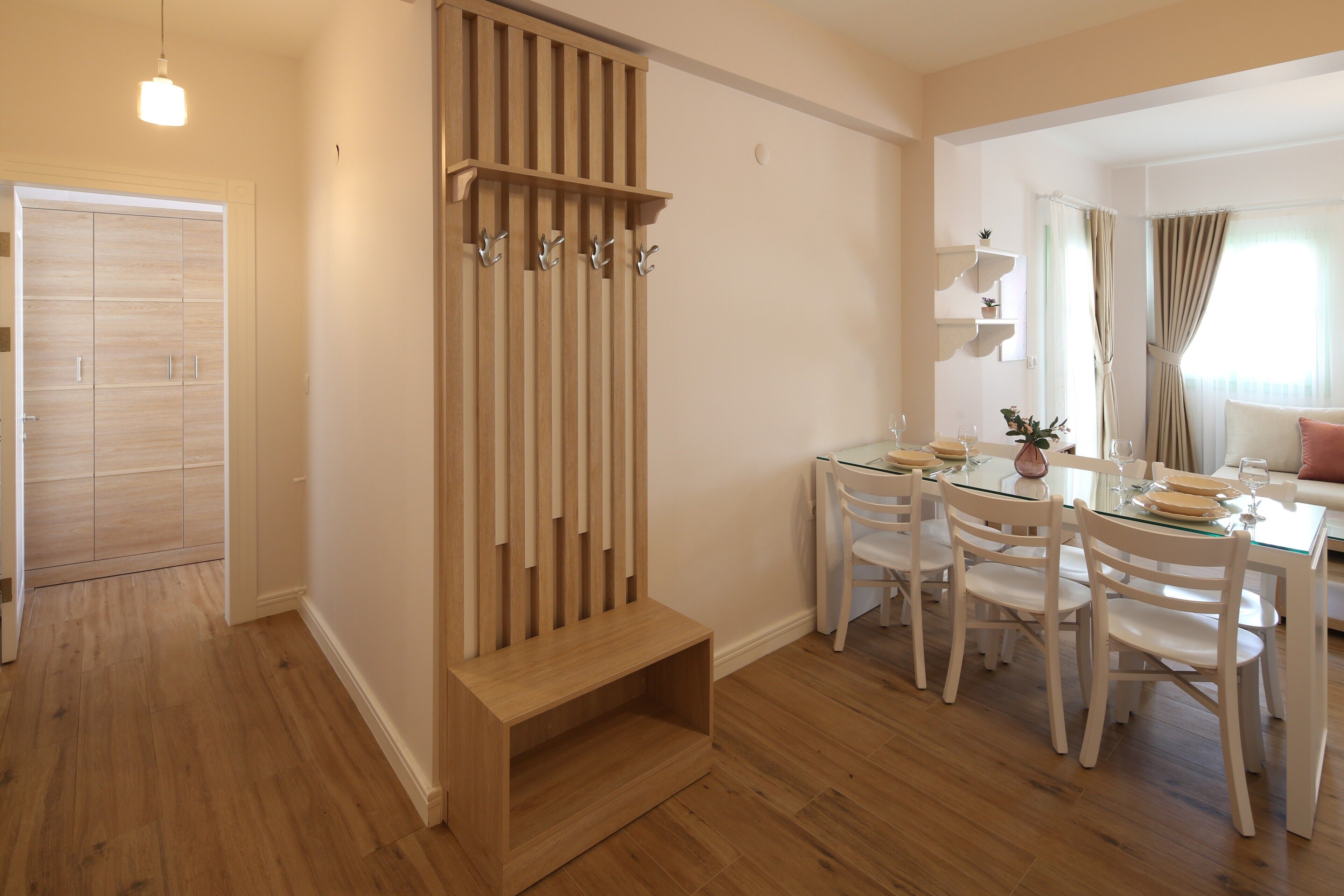 A dining area with a wooden bench, a glass-top table, and white chairs.