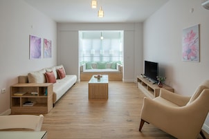 Uma sala de estar moderna com um sofá, uma mesa de centro, uma televisão e uma estante.