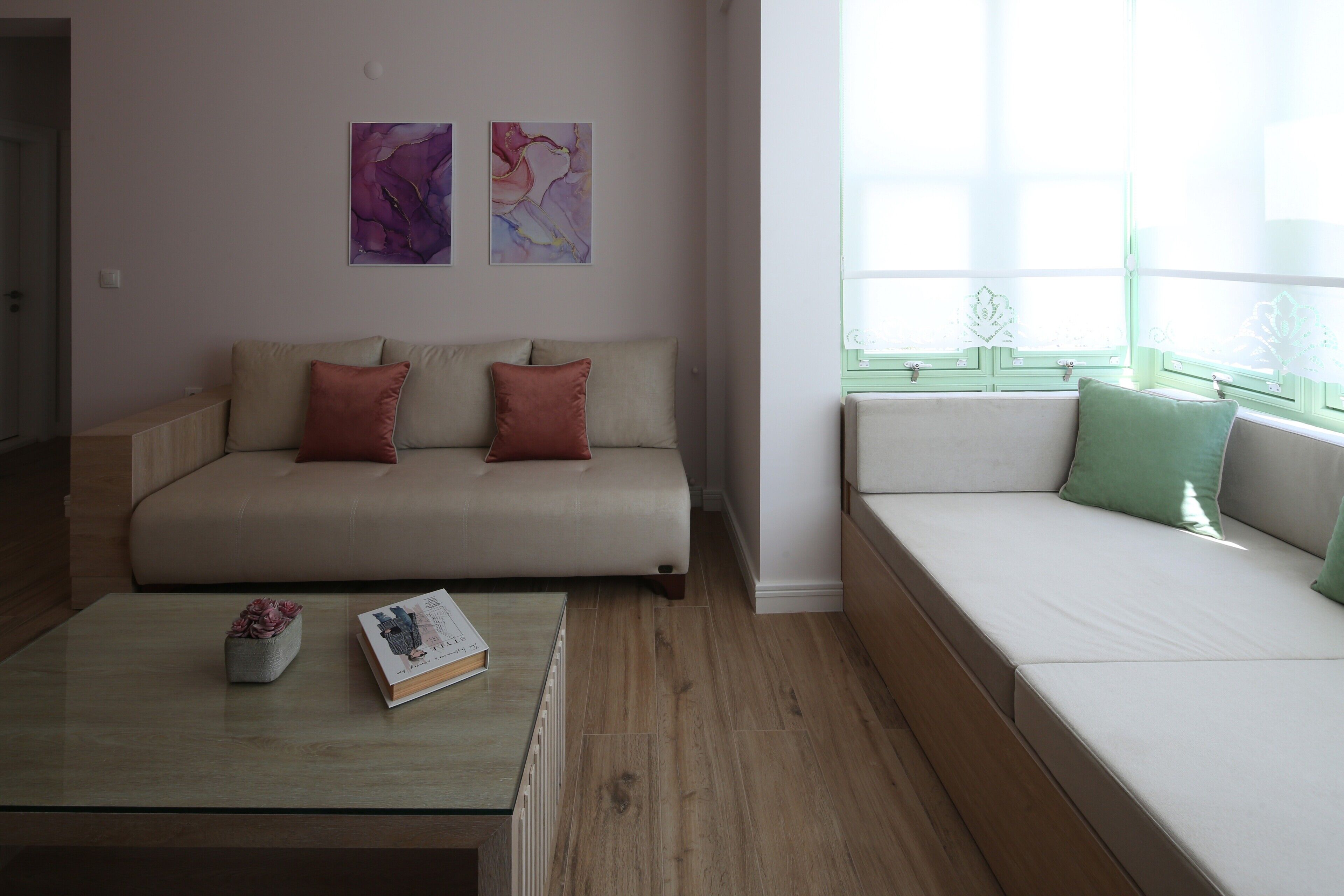 Una sala de estar con un sofá, una mesa de centro con libros y una planta, y obras de arte en la pared.