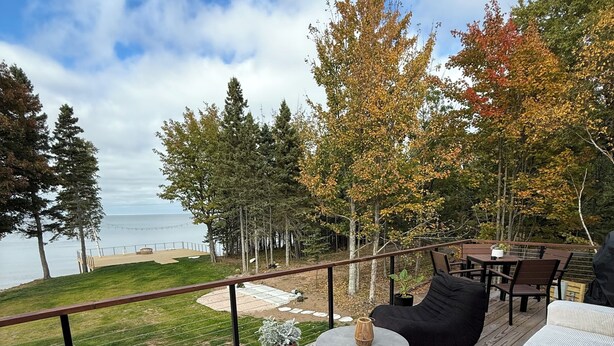 A deck with outdoor furniture, a round table, and a potted plant. - Lake Superior premium bespoke accommodations with ultimate view! (Calumet Township)