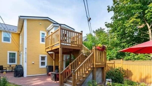 A two-story house with a wooden deck and a red umbrella. - Sunny Home B&B (Charlottetown)
