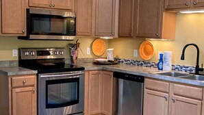 Cocina con armarios de madera, electrodomésticos de acero inoxidable y alfombra azul.
