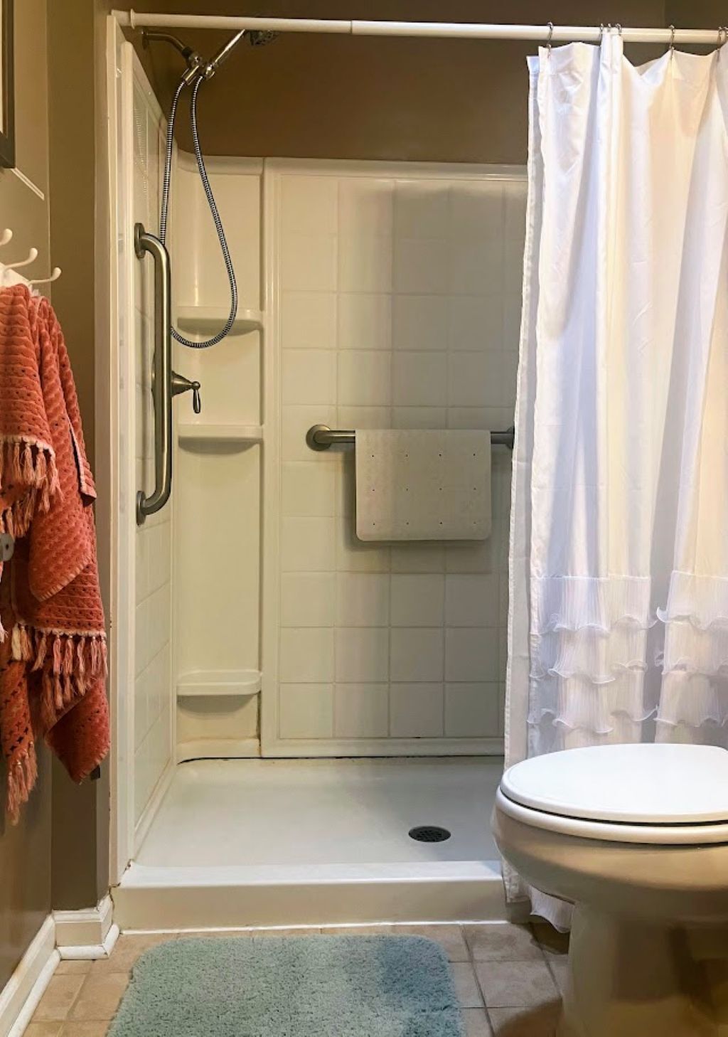 A bathroom with a shower enclosure, a toilet, and a towel rack.