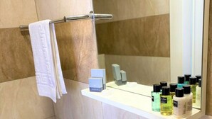 Un baño con un lavabo blanco, un espejo y un estante con artículos de aseo.