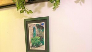 Una habitación con una mesa redonda de vidrio, dos sillas amarillas, un cuadro de un edificio y un aparador de madera.