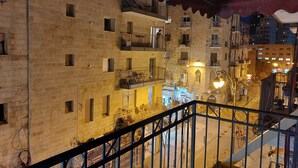 Un edificio de varios pisos con balcones, una escalera y vista a la calle.