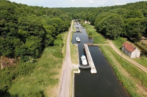 Een rivier met een boot die een sluiscomplex passeert, omringd door weelderige begroeiing.