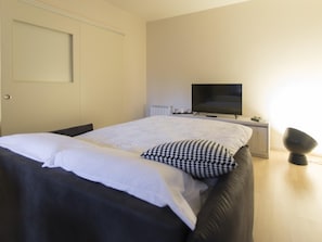 Ein Schlafzimmer mit einem Bett, einem Fernseher, einem Nachttisch und einer Lampe.
