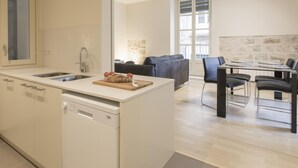 A modern kitchen with a dishwasher, a dining area with a table and chairs, and a large window providing natural light. - Bravissimo Cort Reial 2A, beautifully renovated (Girona)
