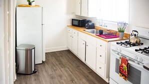 Una cocina compacta con armarios blancos, microondas, tostadora, lavaplatos y estufa.