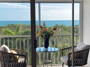 Enjoy the ocean view from this balcony with a round table and two comfortable chairs.