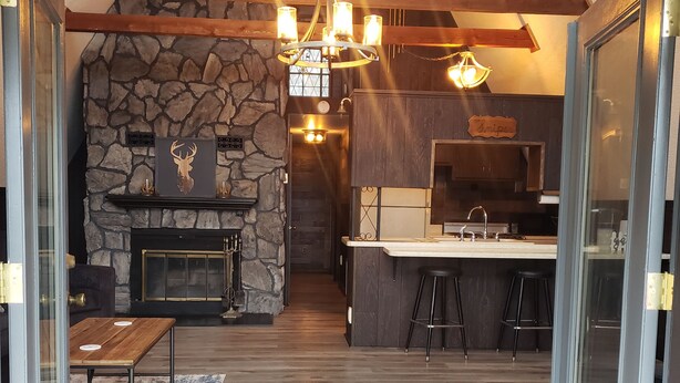 Une cuisine spacieuse dotée d’une cheminée en pierre, de planchers en bois et d’un coin bar avec des tabourets.