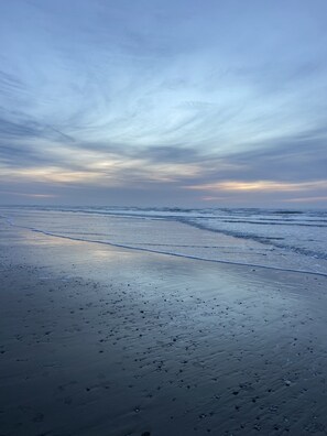 Ein Strand mit feuchtem Sand und sanften Wellen.